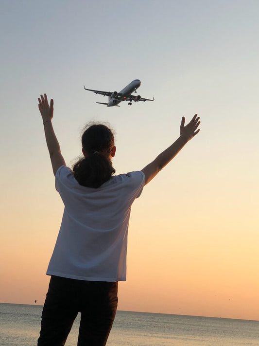 Traveler at an airport with arms outstretched, symbolizing the excitement of air travel while preparing to fly with cremated remains.