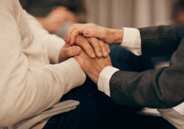 Two people holding hands, offering comfort during the process of choosing a cremation urn.