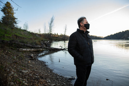 Man standing by the water, reflecting on the choice to scatter a loved one's ashes in a meaningful place.