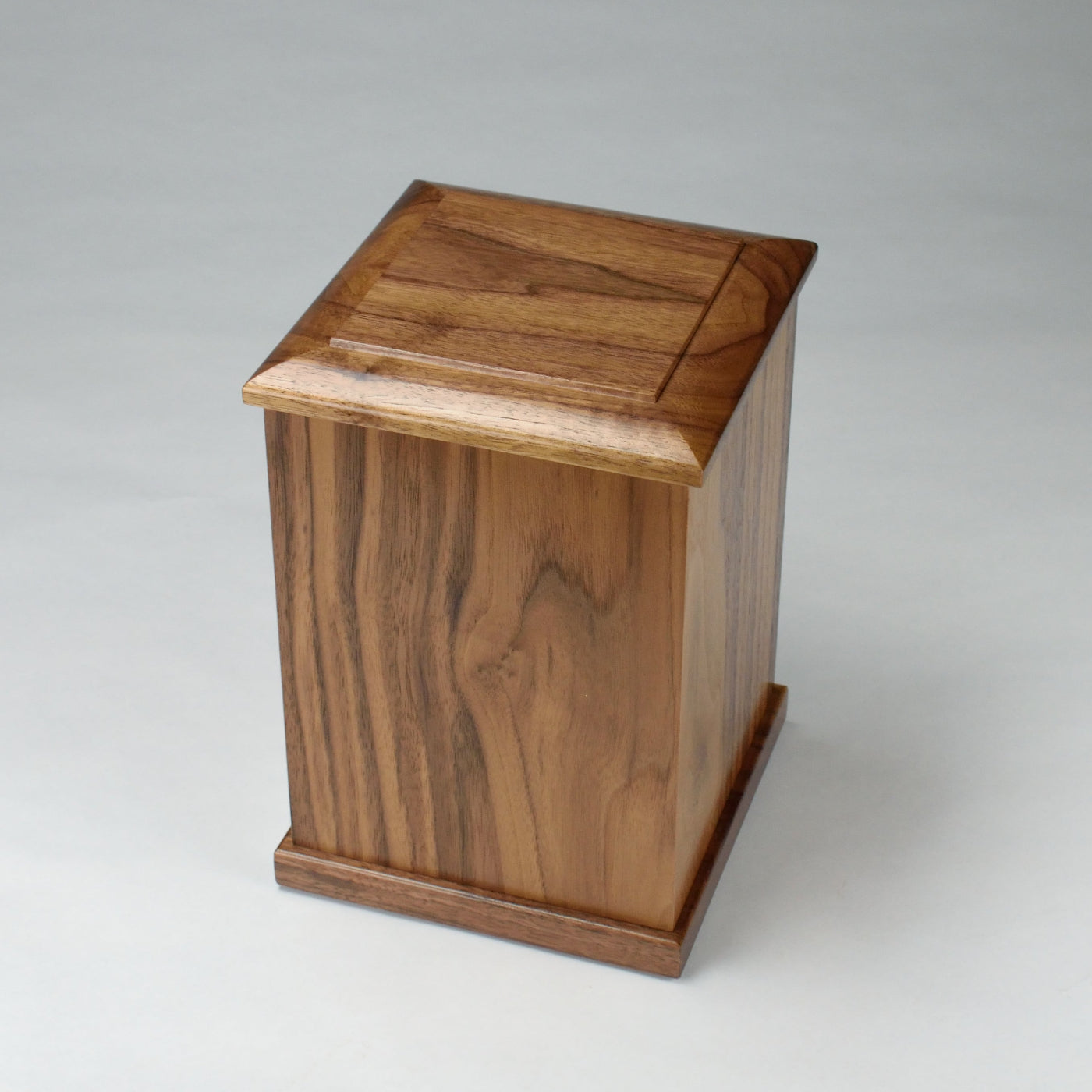 Top-down view of tall walnut cremation urn – showcasing smooth lacquered surface and grain detail